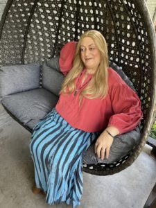 Nicole sitting on a porch swing with a devious smile